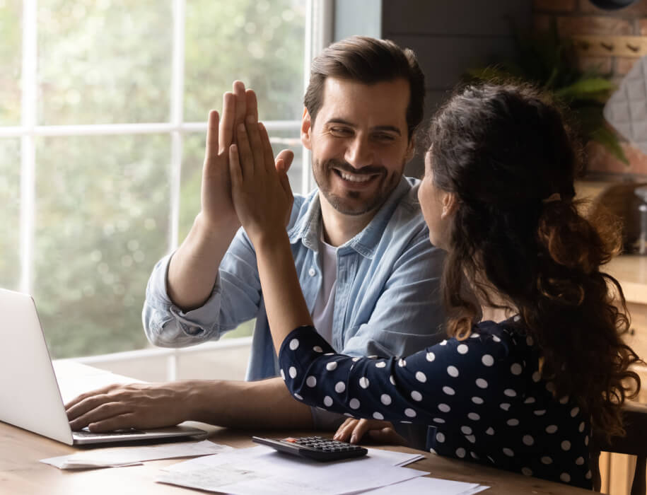 Adult couple high fiving over a laptop