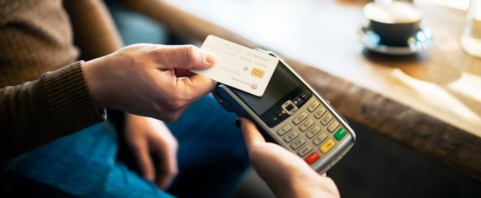 Close-up of a hand holding a credit card on a card reader