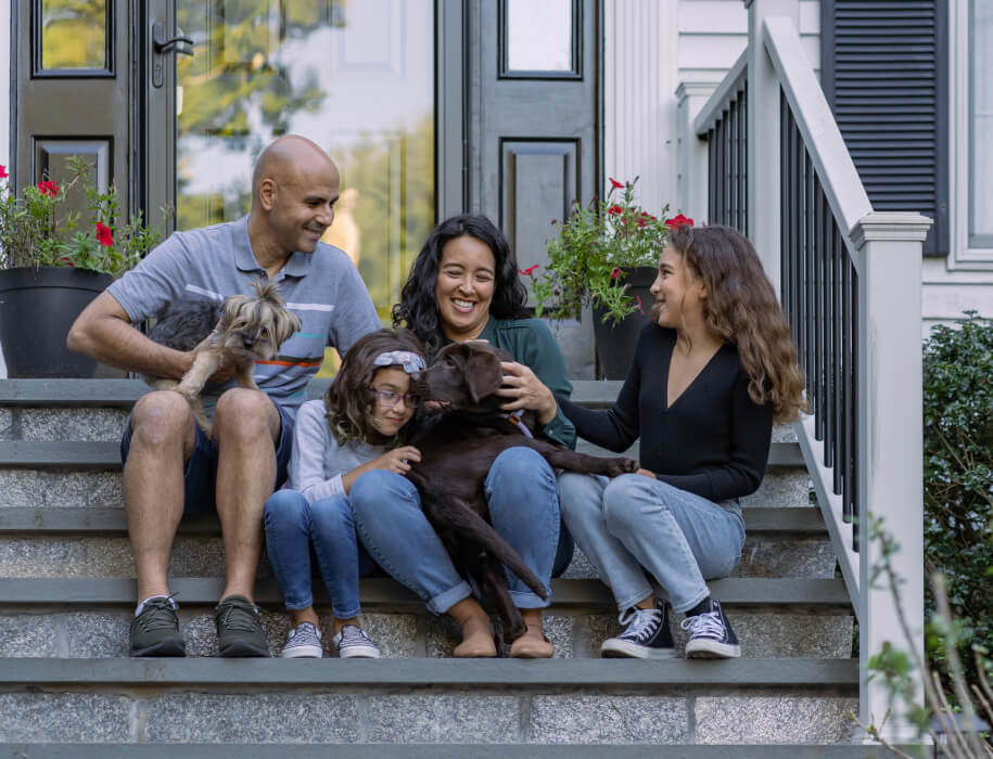 Young family and dog sitting on the front steps of a home